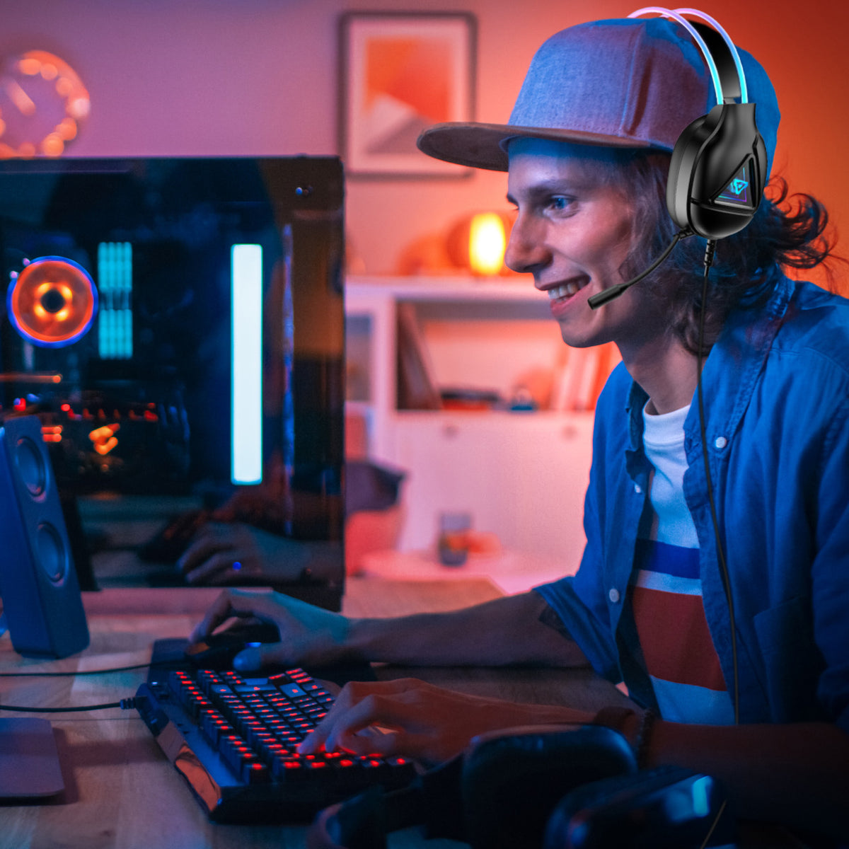 Laser RGB Infinity gaming headphones worn by gamer at PC desk with red backlit keyboard