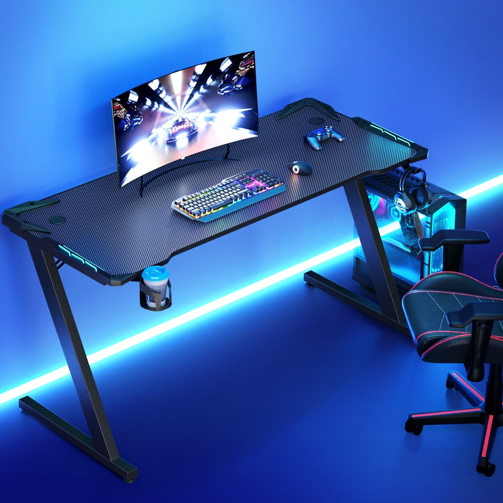 Artiss 140cm RGB gaming desk lifestyle shot with blue under-desk lighting, monitor and gaming chair