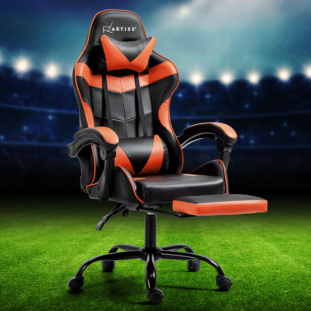 Artiss black and orange gaming chair with footrest staged on a football pitch stadium background
