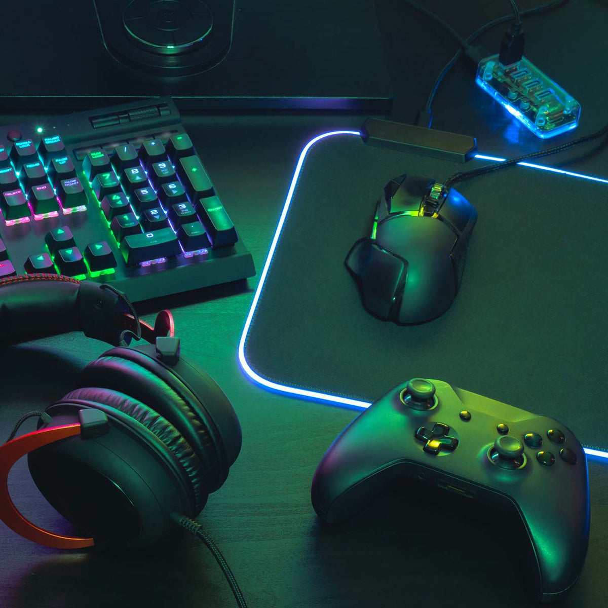 Laser RGB LED gaming mouse pad edge lit white on desk with controller, mouse, keyboard and headphones