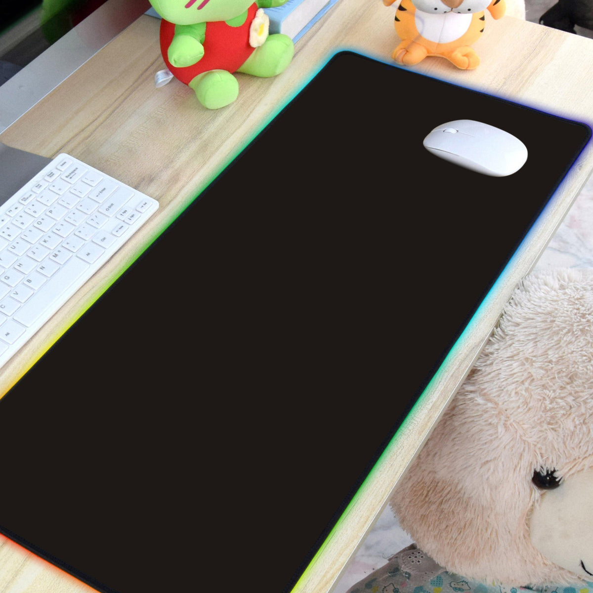 Laser RGB LED gaming mouse pad on a wooden desk with white keyboard and mouse, edge lit rainbow