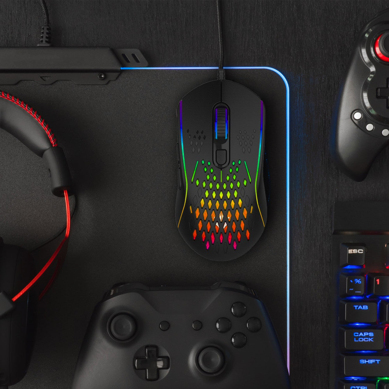 Top down flat-lay of Laser RGB lightweight gaming mouse black with controller, headset and keyboard